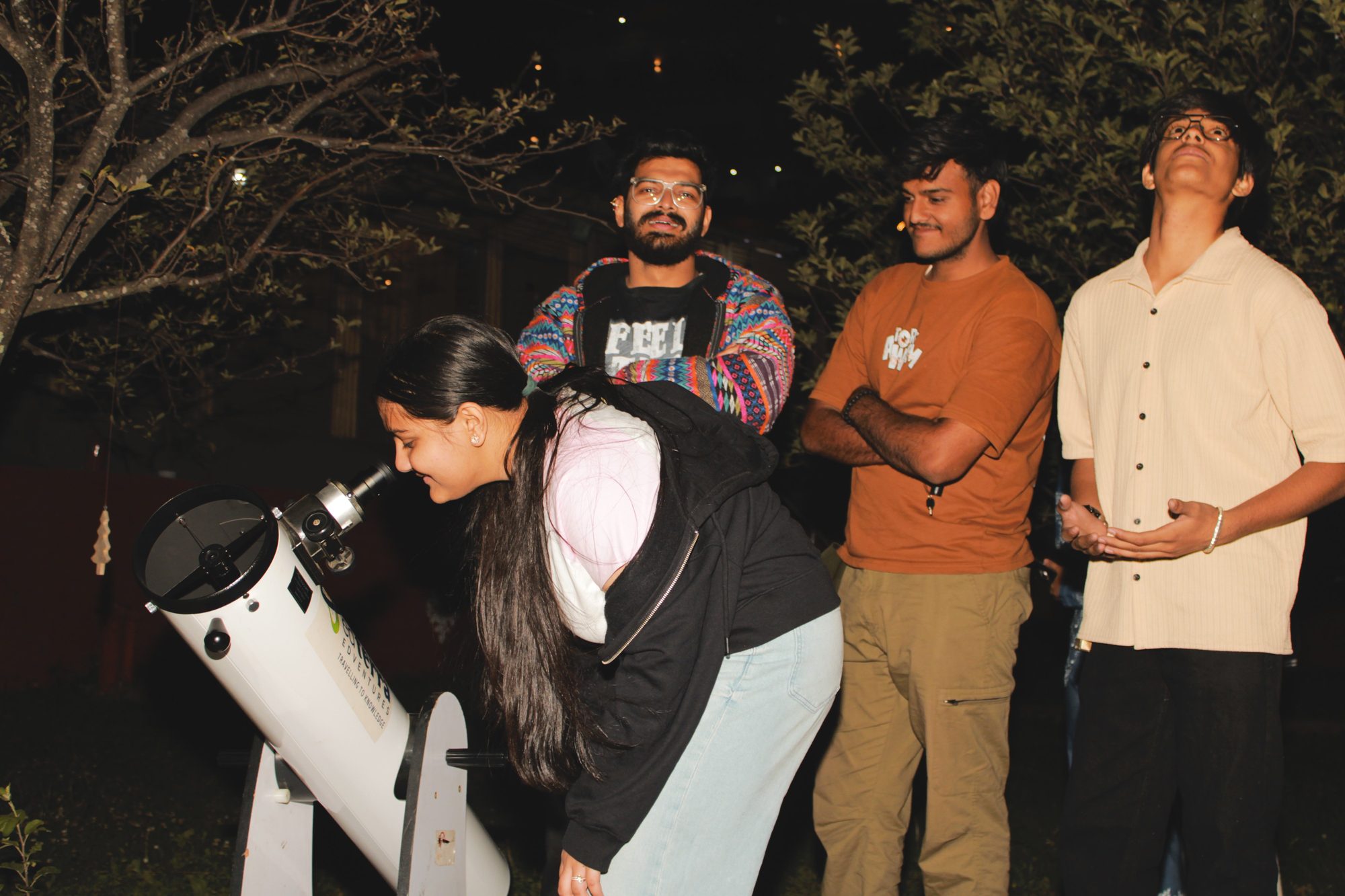 Guests observing through a Dobsonian telescope at night at a resort